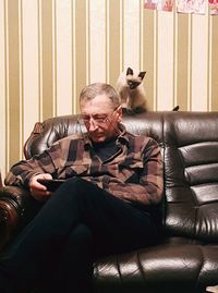 Man holding dog sitting on sofa at home