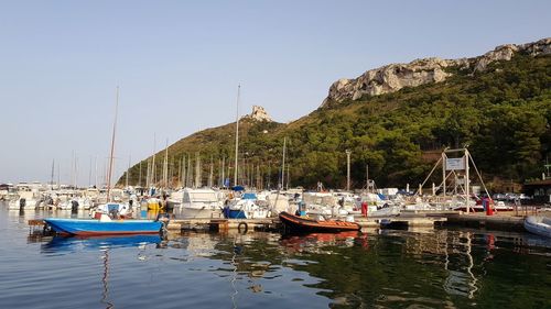 Boats moored at harbor against sky