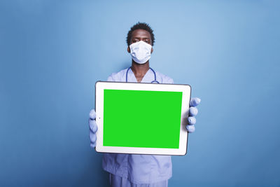 Young woman holding blackboard against blue background