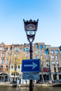 Low angle view of road sign against clear blue sky