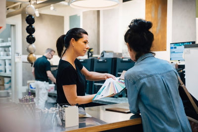 Sales woman showing color swatches to customer at hardware store