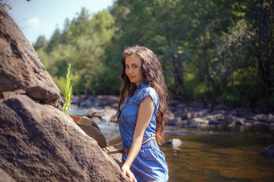 Portrait of young woman standing against stream