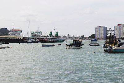 Boats moored in river with city in background