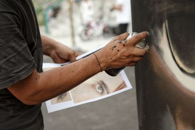 Close-up of man holding hands on metal spray, writers. 