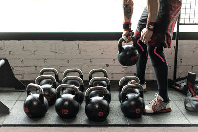 Side view of crop anonymous male athlete choosing heavy kettlebell for active workout in gym