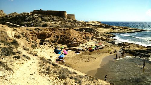 People on beach against clear sky