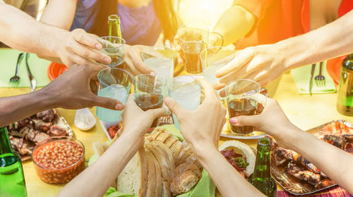 Cropped hands of friends toasting drinks