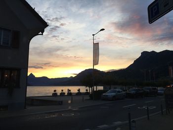 Cars on city against sky during sunset