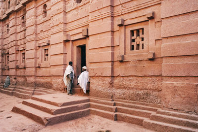 Rear view of men walking on staircase against building