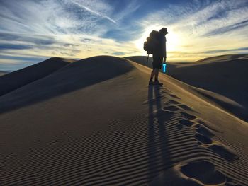 Silhouette man standing at beach against sky during sunset