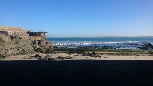 Scenic view of beach against clear blue sky