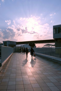 People walking on road at sunset