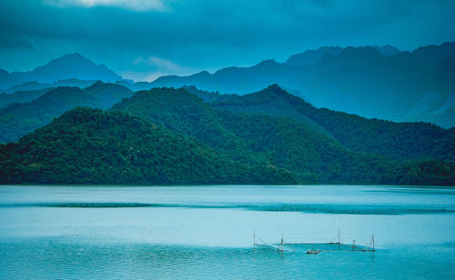 Scenic view of sea by mountains against sky