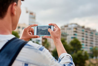 Close-up of a young afro-haired man is taking a photo with his mobile