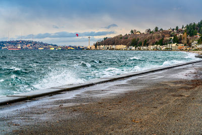 A view of alki beach in west seattle, washington with condos and sea wall on a windy day.