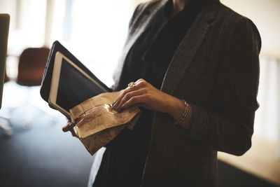 Midsection of female lawyer holding package and digital tablet in office