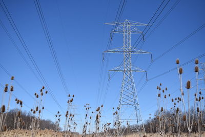 Low angle view of electricity pylon against blue sky