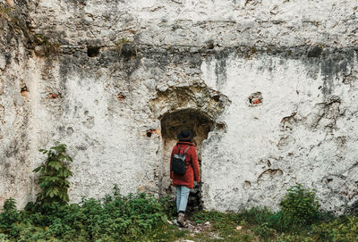 Rear view of woman standing against wall.