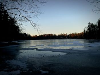 Frozen lake against sky during sunset