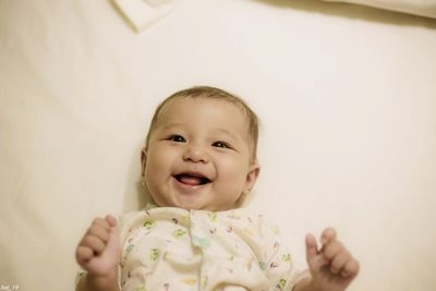 Portrait of cute baby boy lying on bed at home