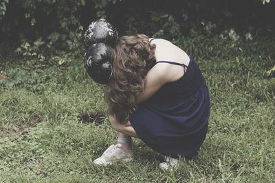 Woman with boxing gloves crouching on grass