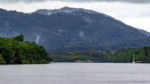 Scenic view of river by mountains against sky