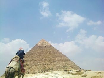 Rear view of man on camel against pyramid