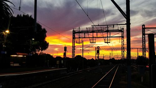 Railroad tracks against dramatic sky during sunset