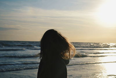 Rear view of man standing at beach against sky