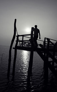 Silhouette of woman in sea at sunset