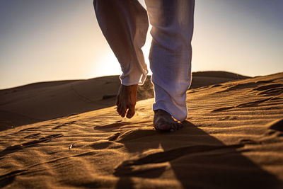 Low section of man walking on sand at beach