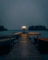 Rear view of person on pier at sea against sky