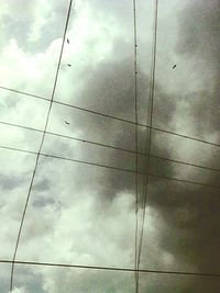 Low angle view of power lines against cloudy sky