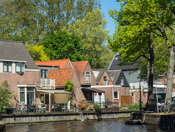 Houses by river in town against sky