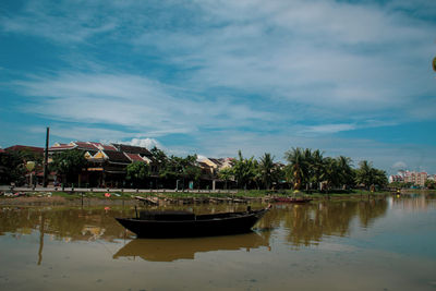 Boats moored on building by houses against sky