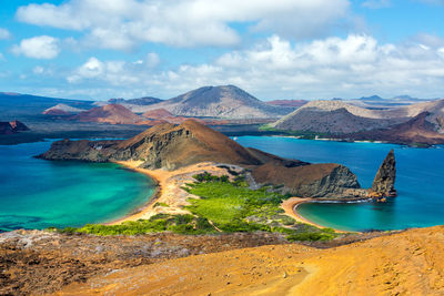 Scenic view of mountain amidst sea at galapagos islands against cloudy sky