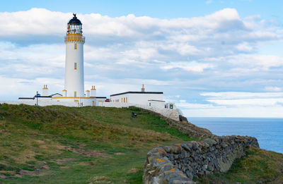 Lighthouse by sea against sky
