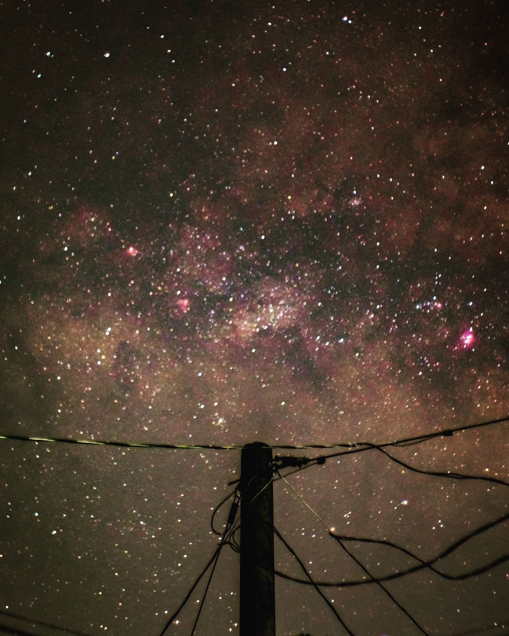 LOW ANGLE VIEW OF ILLUMINATED STAR FIELD AGAINST SKY