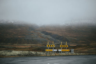 Road signs against mountains during foggy weather