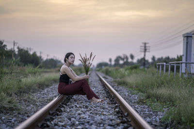 Woman sitting on railroad track