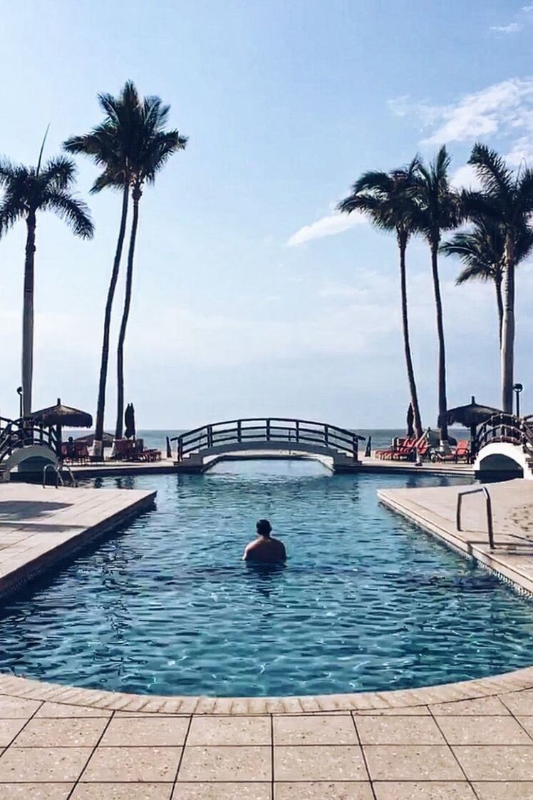 SWIMMING POOL BY PALM TREE ON BEACH