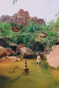 People standing on rock by river against sky