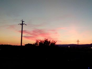 Low angle view of silhouette electricity pylon against sky during sunset