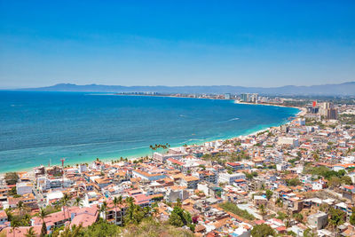 High angle view of city by sea against blue sky