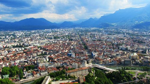 Aerial view of cityscape against cloudy sky