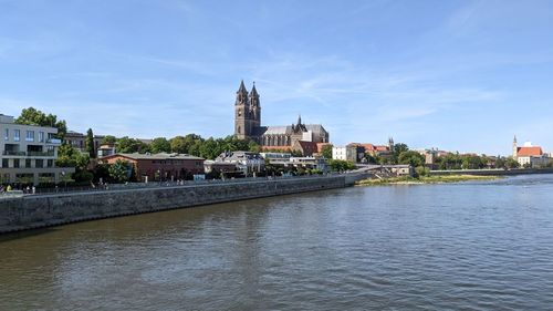 Buildings by river against sky in city