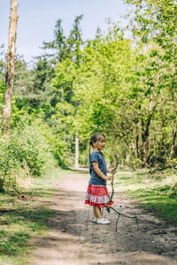 Full length of girl standing on dirt road in forest