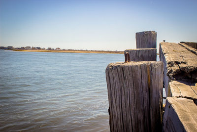 Wooden posts in front of sea against clear sky