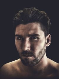 Portrait of young man against black background