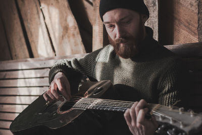 Midsection of man playing guitar